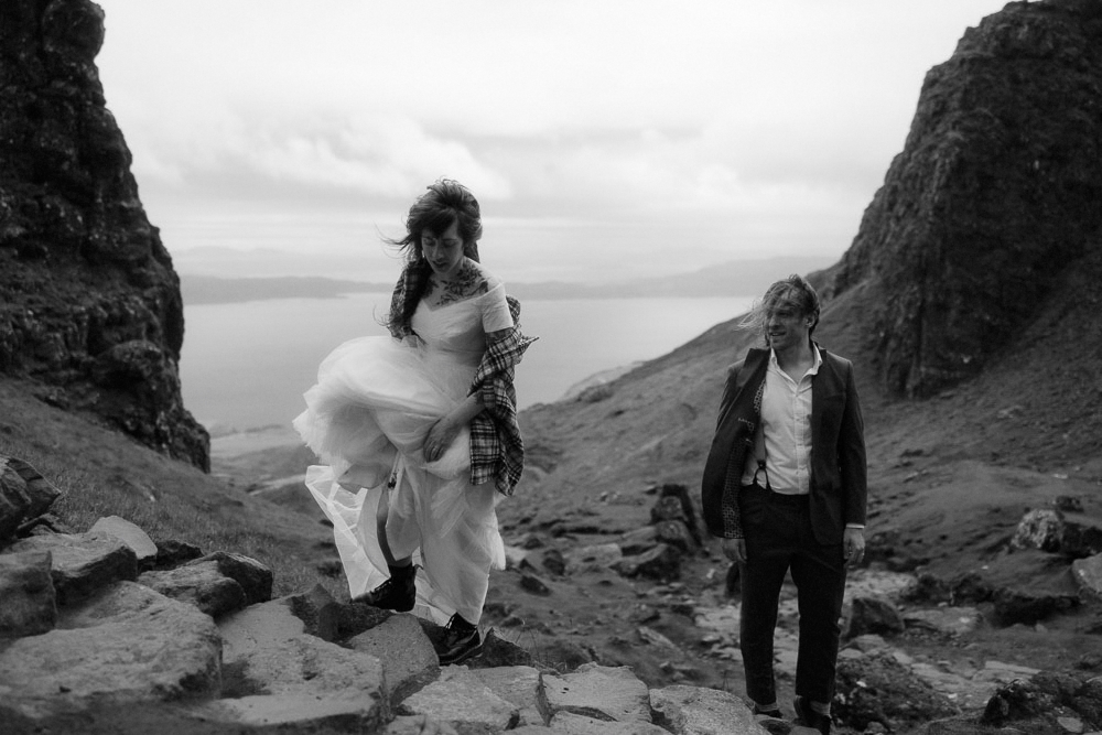 A couple climb a mountain in their wedding clothes on their elopement day in Scotland