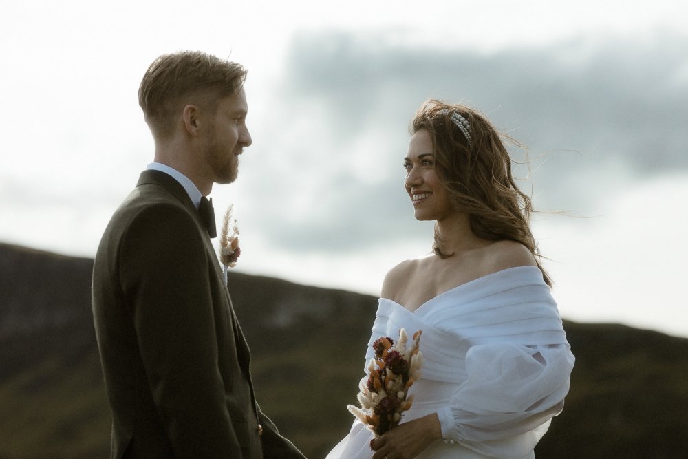 A couple in the middle of their wedding ceremony taking place outdoors in the Scottish Highlands