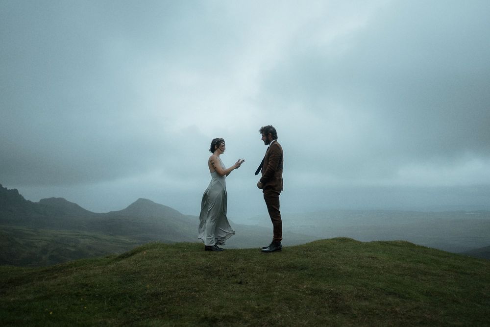 A bride and groom stand on top of a mountain and read their vows during their elopement ceremony on the Isle of Skye, Scotland