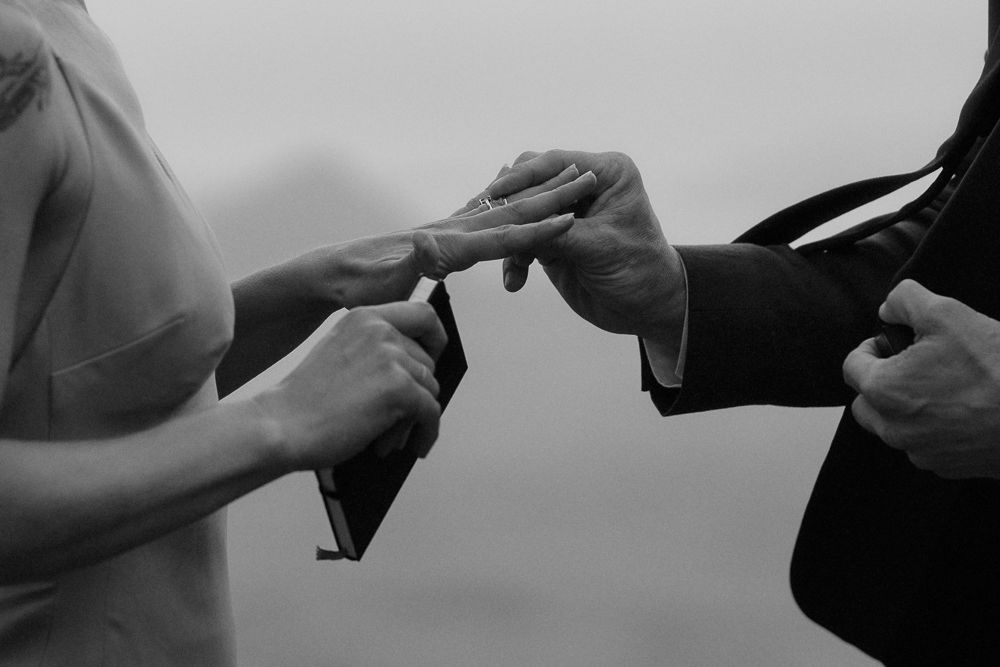 Groom puts a wedding ring on his bride's finger during a moody elopement on the Isle of Skye, Scotland