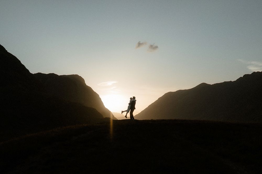 Groom picks his bride up during sunset after their elopement in Glencoe, Scotland