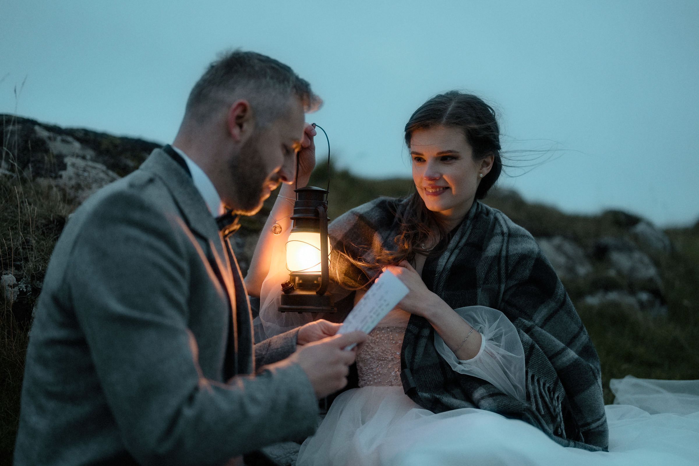 Couple share vows under the light of a lantern on the Isle of Skye after their intimate evening Scottish elopement
