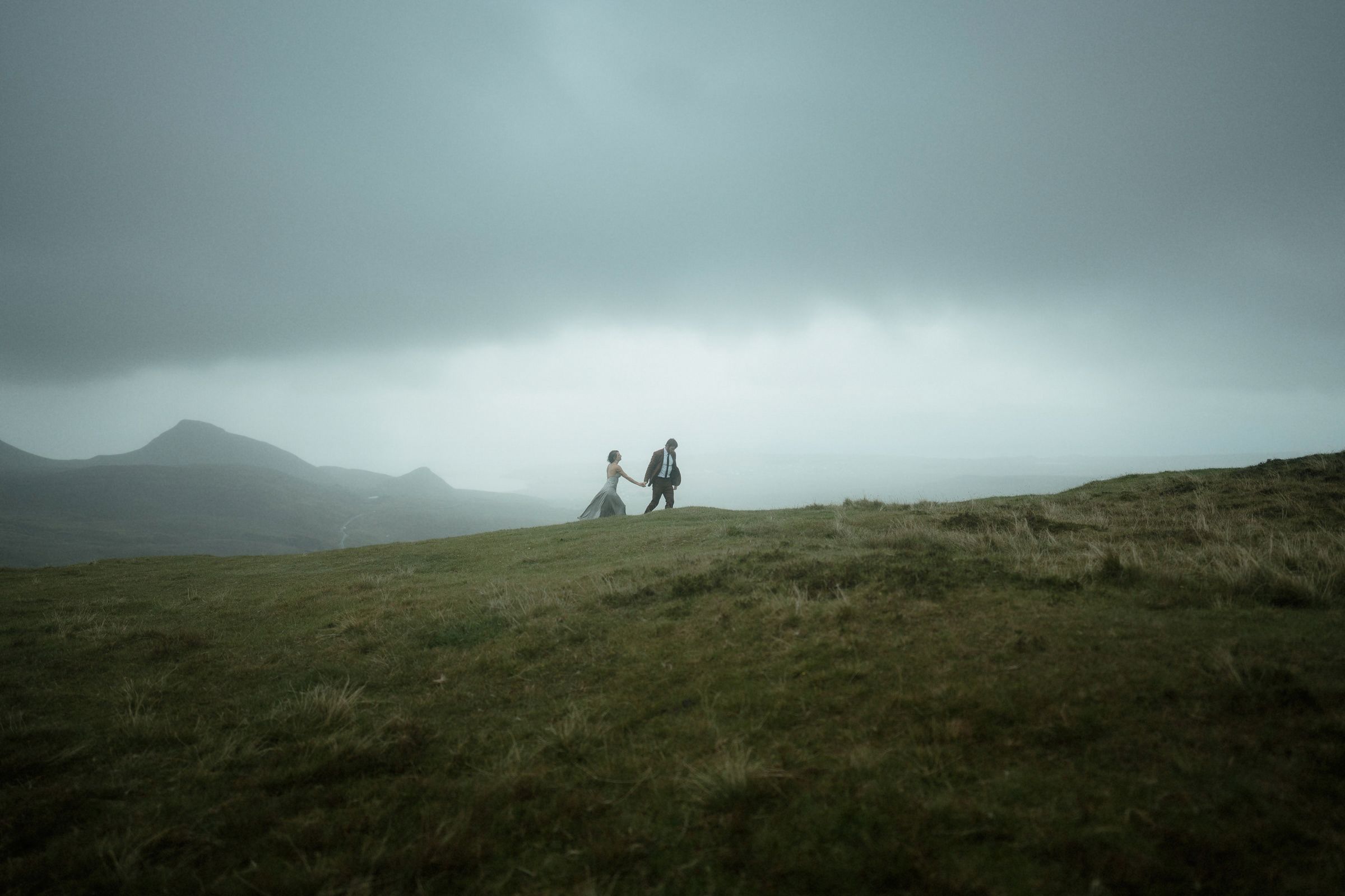 Couple climb a hill hand in hand at Fairy Glen on the Isle of Skye after their elopement in Scotland
